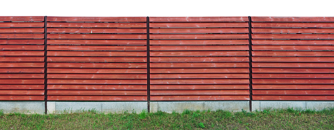 Long rustic wooden fence made of red horizontal boards isolated panoramic outdoor object