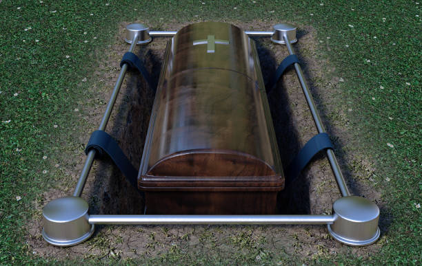 Modern Coffin Into Grave A modern wooden coffin at a funeral being lowered into a grave with a lowering mechanism a dirt and grass background - 3D Render funeral expense stock pictures, royalty-free photos & images