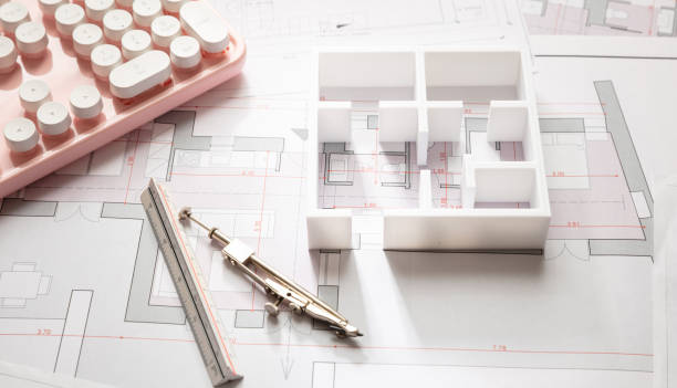 istock Construction concept. Residential building blueprint drawings and a pink computer keyboard 1187544337