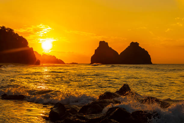 Stunning sunset at Cacimba do Padre beach in Fernando de Noronha, Brazil The two peaks in the picture are called Morro dos Dois Irmãos. Cacimba do Padre beach is one of the most popular and beautiful beaches in this archipelago. archipelago photos stock pictures, royalty-free photos & images