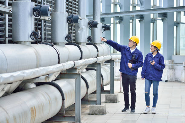 due colleghi ingegneri che esaminano le apparecchiature della torre di raffreddamento - industria chimica foto e immagini stock