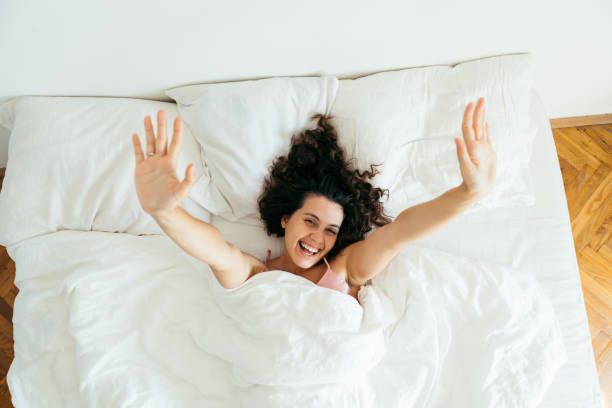 istock young pretty woman in bed with white sheets bright light copy space 1187553105