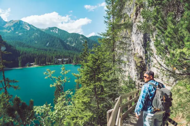 Photo of man walking by hiking trail around braies lake in italy dolomites mountains. activity leisure lifestyle