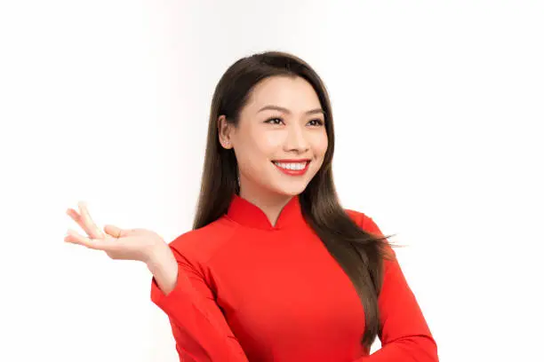 Smiling Vietnamese woman in ao-dai dress holding something in her hand