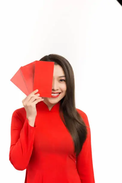 Close up Vietnamese woman dress in traditional aodai and hold red envelope on white background