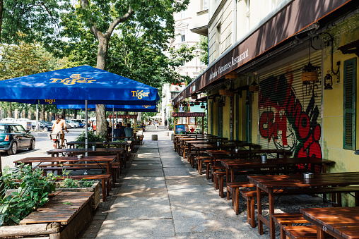 Berlin, Germany - July 29, 2019: Vietnamese restaurant with tables and umbrellas on sidewalk in Kreuzberg quarter. Kreuzberg is one of the cultural centers of Berlin.