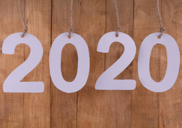 istock Twenty twenty numbers hanging on decorative ropes, highlighted in closeup on a brown background 1187565884