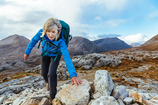 Senior woman climbing on the Beinn Eighe Mountain Trail, Scotland.