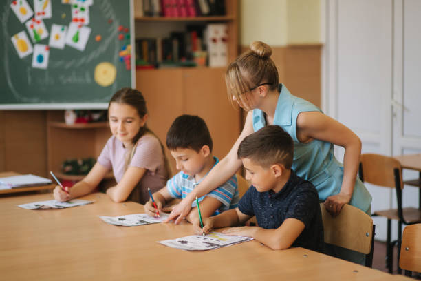 istock Teacher helping school kids writing test in classroom. education, elementary school, learning and people concept 1187566728