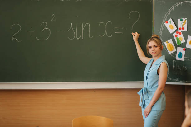 istock Female teacher whiting thomething on school desk. Young teacher 1187567452