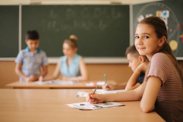istock Group of school kids with pens and notebooks writing test in classroom. education, elementary school, learning and people concept 1187567805
