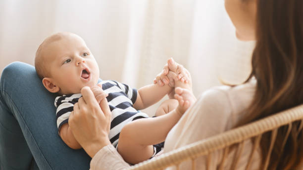 entzückende neugeborene baby cooing, während auf dem schoß der mutter liegen - human teeth child smiling family stock-fotos und bilder