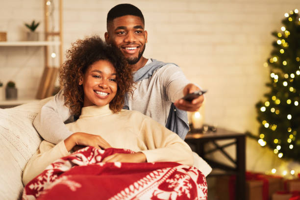 casal afro apaixonado na véspera de natal desfrutar assistindo tv - family sofa night indoors - fotografias e filmes do acervo