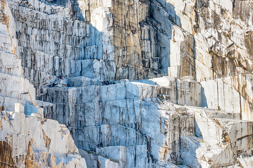 Detail of an Italian Marble quarry or open cast mine pit showing the rock face where the stone is excavated in blocks for construction and sculpture in Carrara, Italy