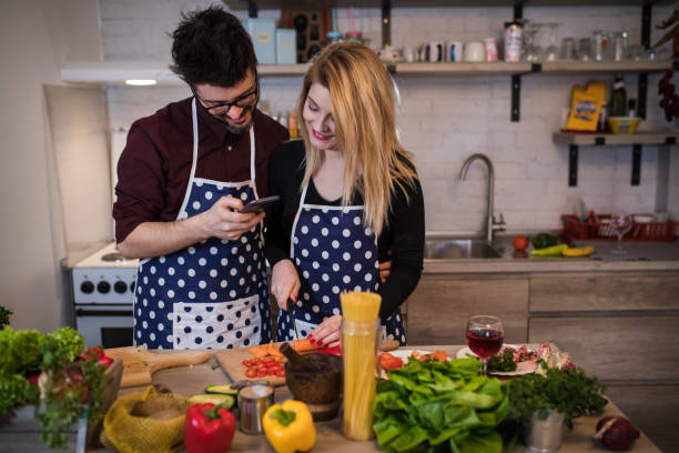 istock Happy young couple in a home kitchen taking a selfie with a smart phone while preparing healthy food. 1187572046