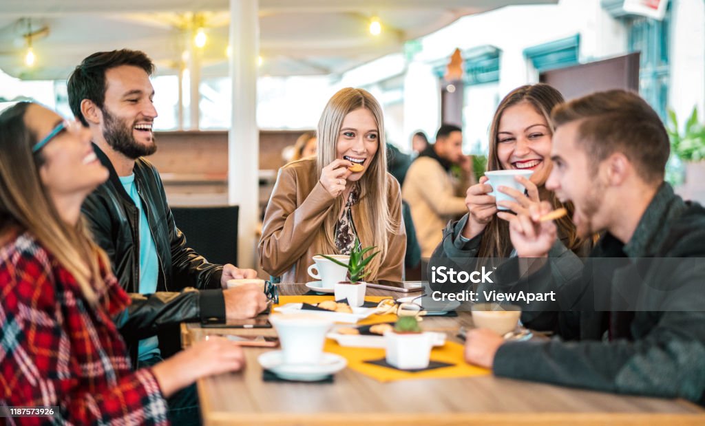 커피 바에서 카푸치노를 마시는 친구 그룹 - 사람들이 이야기하고 멋진 카페테리아에서 함께 재미를 - 레스토랑 카페에서 행복한 남자와 여자와 우정 개념 - 따뜻한 전구 조명 필터 - 로열티 프리 먹기 스톡 사진