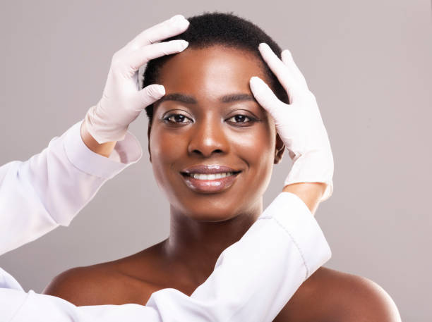 bella donna afroamericana che si cura alla clinica di cosmetologia - plastic beauty injecting protective glove foto e immagini stock