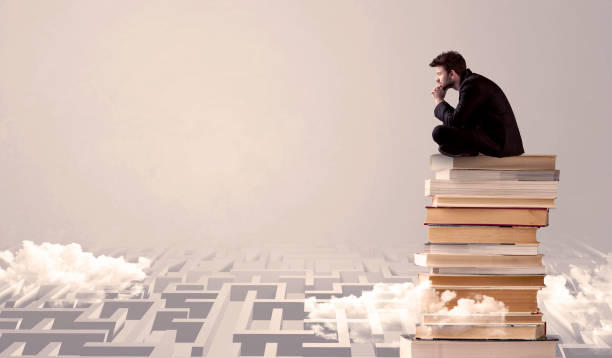 istock Businessman sitting on books in labirynth 1187575914