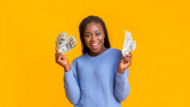 menina afro feliz com dinheiro do dólar sobre o fundo amarelo - holding money - fotografias e filmes do acervo