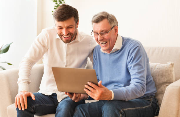istock Man Teaching Elderly Father E-Literacy On Laptop Sitting On Sofa 1187577447