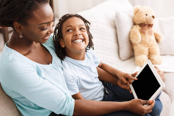 african-american mom and daughter using digital tablet - digital tablet women enjoyment happiness imagens e fotografias de stock