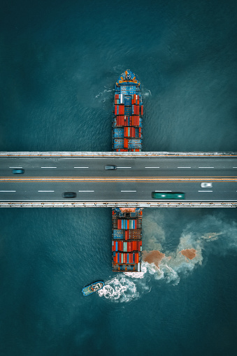 Container freight ship sailing under a road bridge