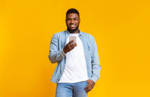 istock Handsome african man holding phone and smiling at camera 1187579455