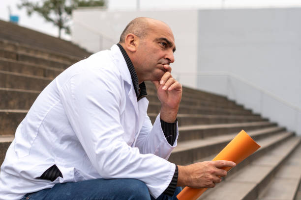 istock Thoughtful doctor sitting outdoors 1187580453