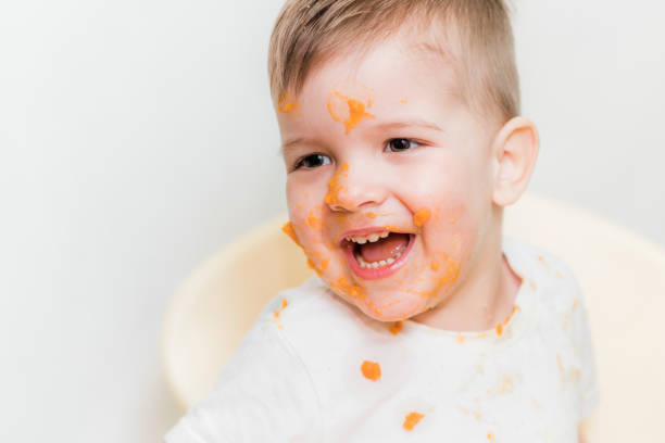 istock cute baby boy while eating smeared his face with a pumpkin 1187580914