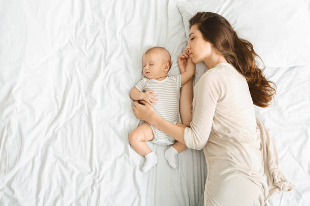 millennial mother embracing her cute little baby during sleep - baby mother sleeping child imagens e fotografias de stock