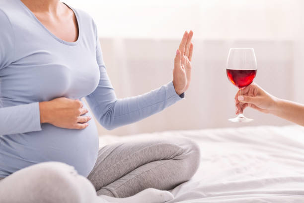 irriconoscibile ragazza incinta che si rifiuta di portare il vino seduto sul letto - abdomen addiction adult alcohol foto e immagini stock