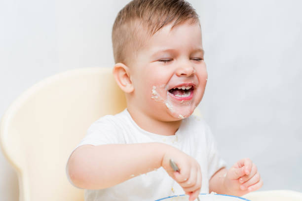 istock adorable baby boy eats porridge with a small spoon himself 1187581830