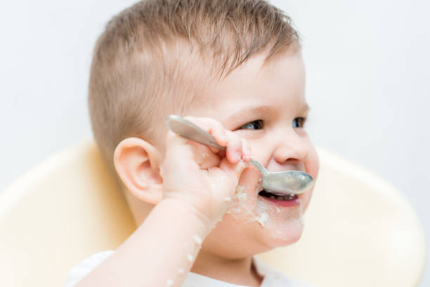 istock adorable baby boy eats porridge with a small spoon himself 1187582092