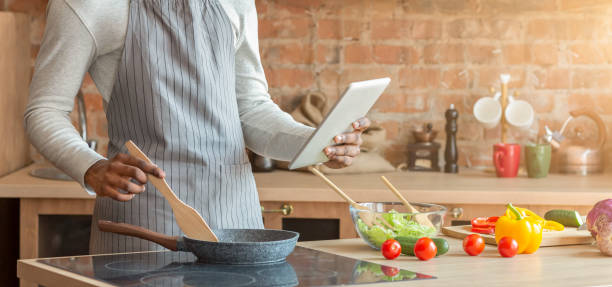 Man holding digital tablet and cooking at kitchen