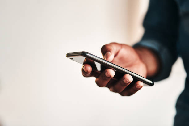 Staying connected in this digital age Cropped shot of an unrecognizable businessman standing alone in his home office and texting on his cellphone telephone stock pictures, royalty-free photos & images