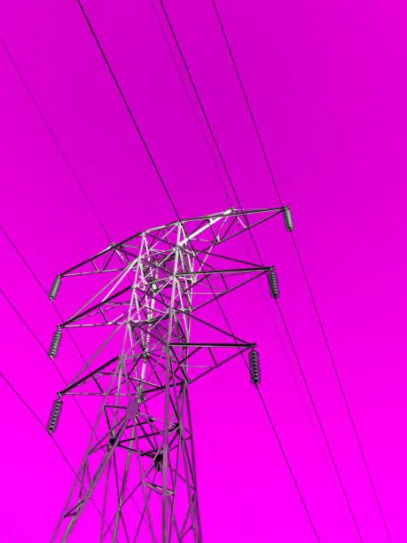Photo of High towers of a high-voltage power line on a pink-purple background, bottom view