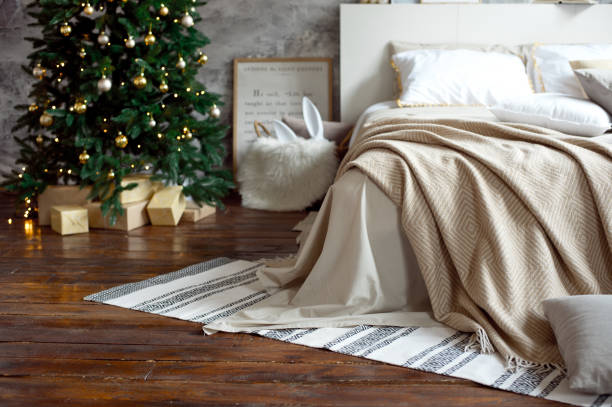クリスマスのアパートの装飾、スカンジナビアの居心地の良い家の装飾、クリスマスツリーの隣に暖かいニット毛布とベッド。ライトと花輪。 - christmas textile blanket decoration ストックフォトと画像