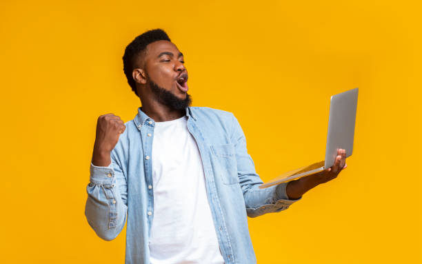 Ecstatic black guy watching football online on laptop Goool. Ecstatic black guy watching football online on laptop and cheering his favorite team. raised fist photos stock pictures, royalty-free photos & images