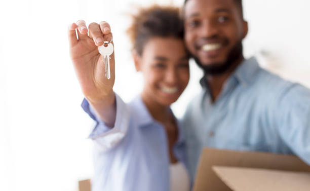 istock Happy Afro Couple Showing Keys Embracing Standing Indoor, Selective Focus 1187584921