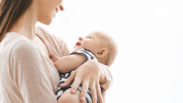 giovane donna sorridente cullando il suo bambino appena nato in braccio - childrens music foto e immagini stock