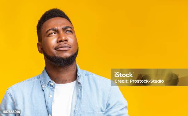 Portrait Of Suspicious Black Guy Looking Upwards At Copy Space Stock Photo - Download Image Now