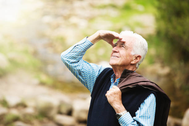 istock Senior man walking in forest looks up curiously 1187586083