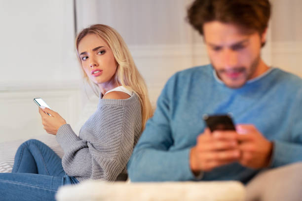 istock Wife Watching Husband Chatting On Cellphone Sitting On Couch Indoor 1187586439