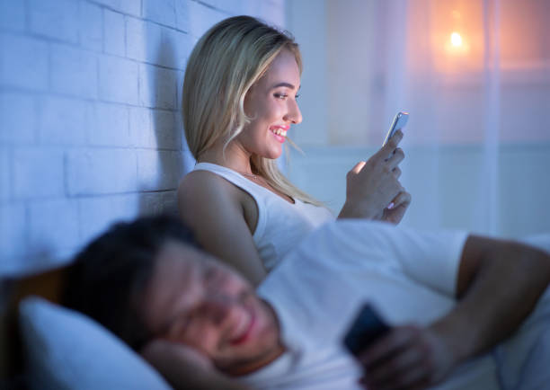 istock Couple Texting On Phone Lying In Bed At Night 1187587324