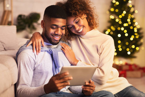 glückliches afro-paar mit video-anruf am weihnachtsabend - christmas shopping internet family stock-fotos und bilder