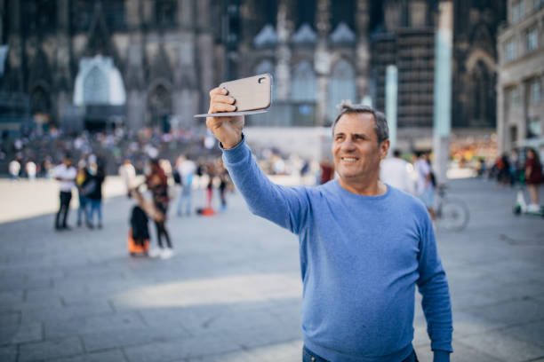 istock Older man is in a tourist destination, using a cell phone 1187587625