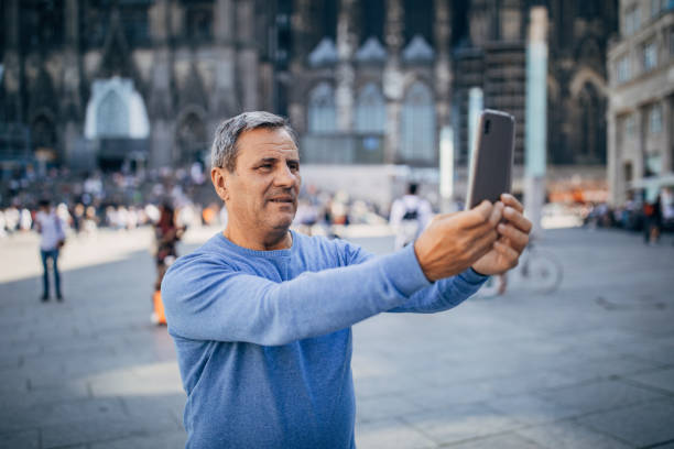 istock Older man is in a tourist destination, using a cell phone 1187587633