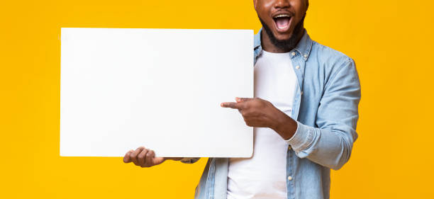 istock African guy holding white advertising board and pointing on it 1187587730