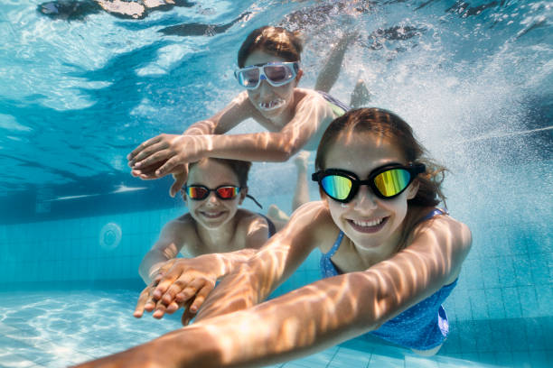 bambini felici che nuotano sott'acqua in piscina - cheerful swimming pool happiness resort swimming pool foto e immagini stock