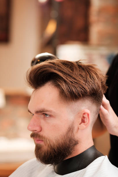 istock Fashionable man with a beard makes hair styling 1187592139